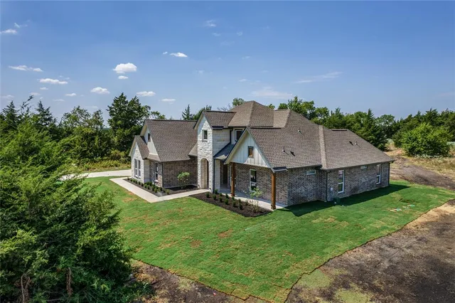 a aerial view of a house with a big yard and large tree