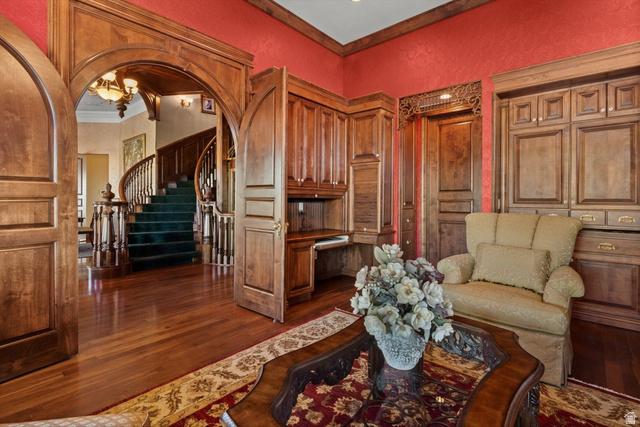 5615 East Eight Mile Gap Road Kanab, UT 84741 - Photo 31 of 81 Living room with arched walkways, a chandelier, dark wood-style floors, a textured wall, and ornamental molding