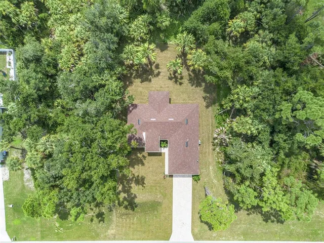 an aerial view of a house with a yard and trees all around