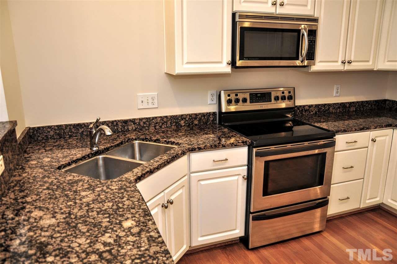 6902 Ray Road Raleigh, NC 27613 - Photo 3 of 23 a kitchen with granite countertop white cabinets and black appliances