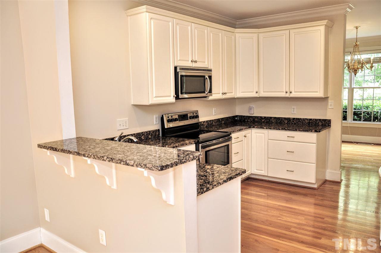 6902 Ray Road Raleigh, NC 27613 - Photo 5 of 23 a kitchen with granite countertop white cabinets and black appliances