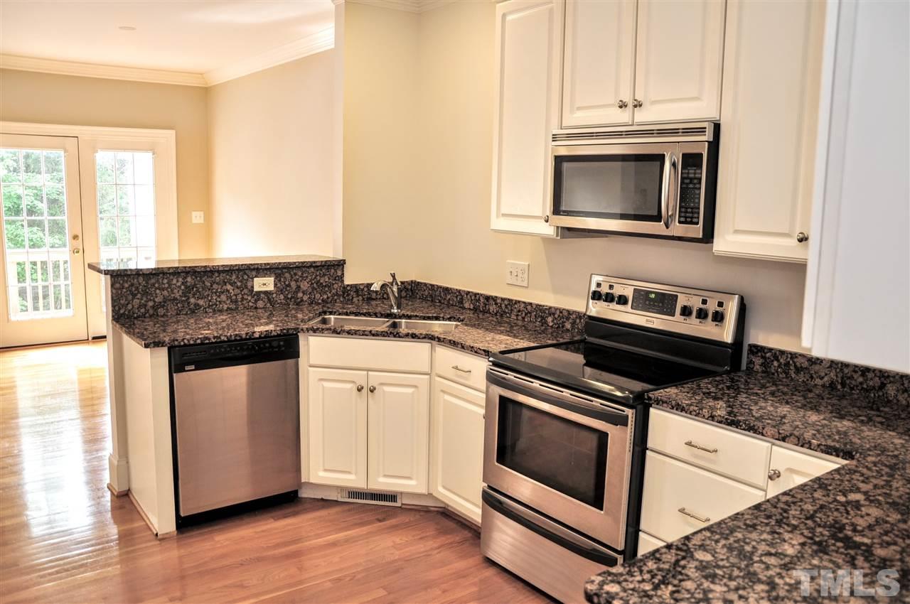 6902 Ray Road Raleigh, NC 27613 - Photo 6 of 23 a kitchen with granite countertop white cabinets and black appliances