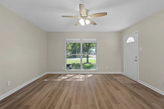 a view of an empty room with wooden floor and a window