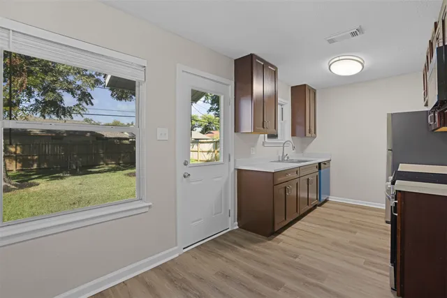 a kitchen with stainless steel appliances granite countertop a refrigerator a sink a stove and wooden floors