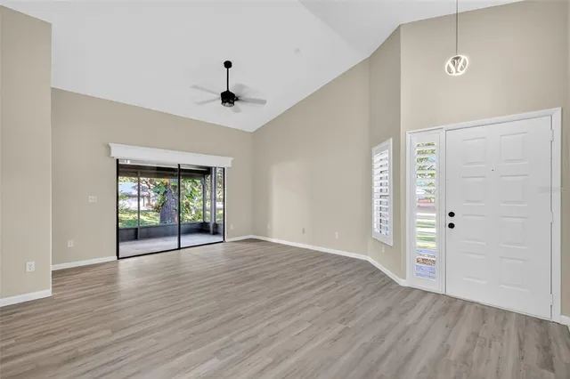 a view of an empty room with window and wooden floor