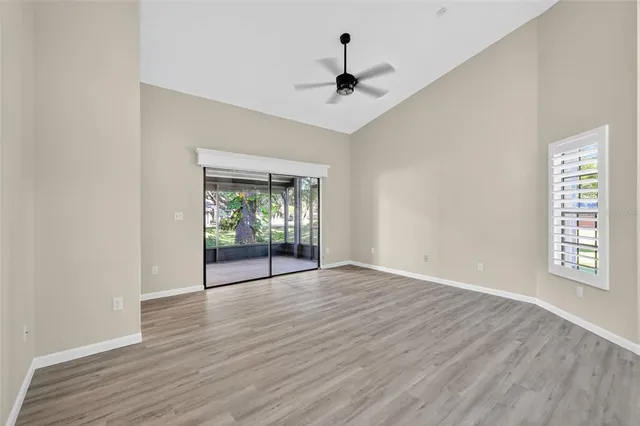 a view of an empty room with window and wooden floor
