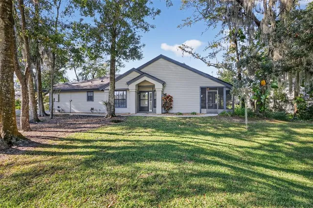 a view of a house with a big yard and large trees