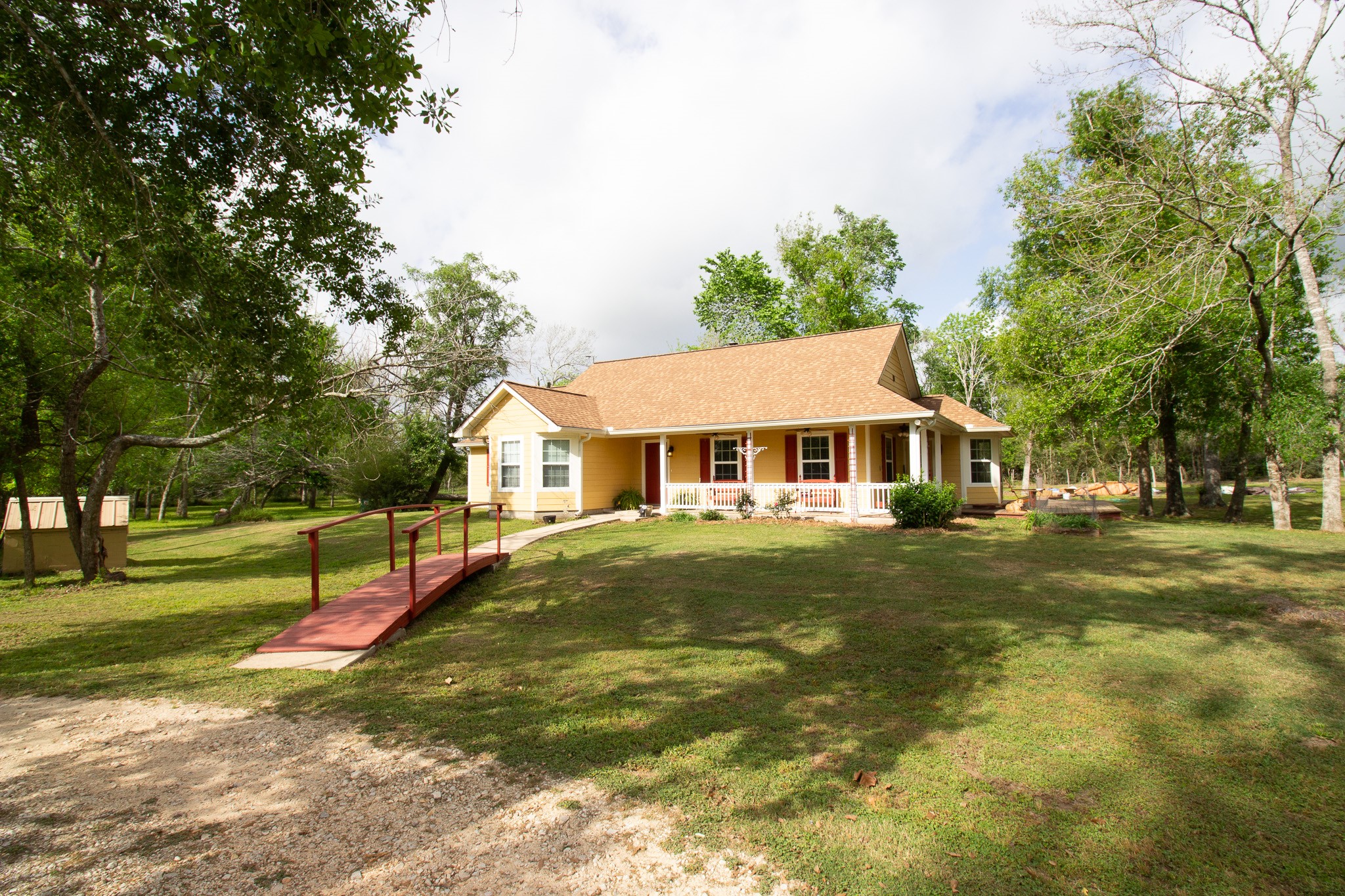 40411 Bosque Road Hempstead, TX 77445 - Photo 3 of 25 Charming country home with a welcoming front porch, beautifully complemented by a quaint private bridge that adds character and a peaceful, storybook entrance to the property.