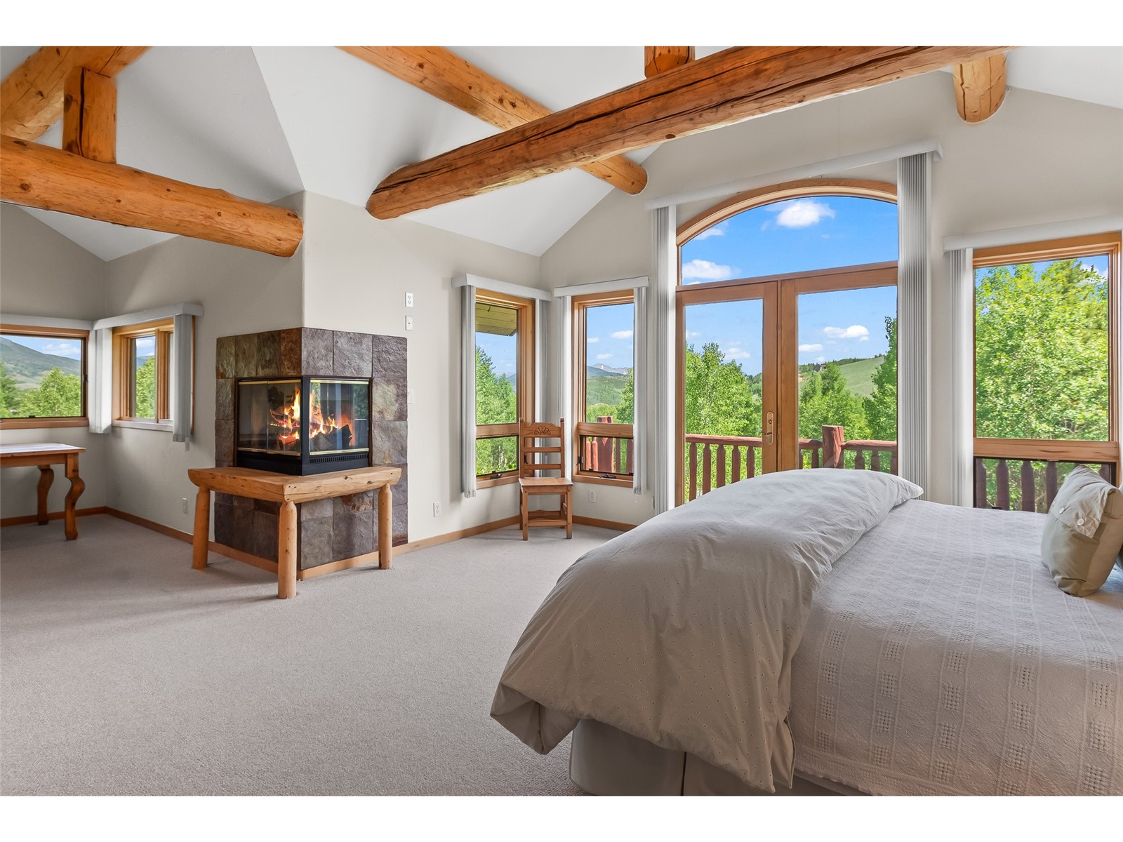 1746 South Ruby Road Silverthorne, CO 80498 - Photo 31 of 50 Primary Bedroom with multiple windows, a tiled fireplace, and carpet flooring