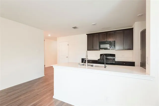 a kitchen with stainless steel appliances a sink a stove a microwave a sink and a refrigerator