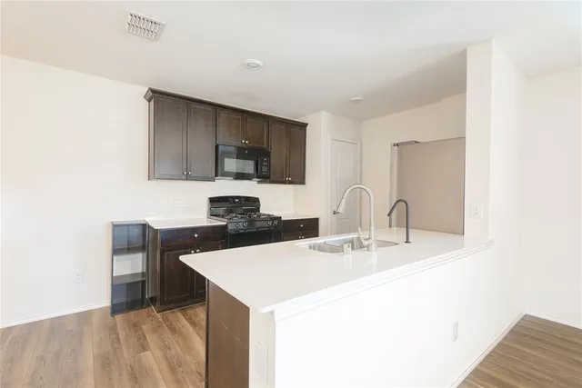 a kitchen with stainless steel appliances a sink a stove a microwave a counter top space and cabinets