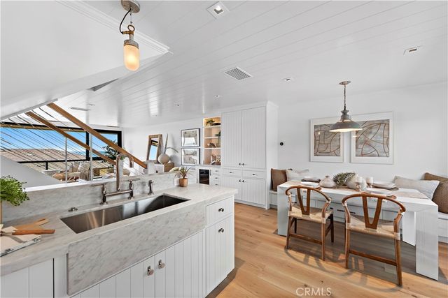 a kitchen with stainless steel appliances kitchen island granite countertop a refrigerator a stove a dining table and chairs with wooden floor