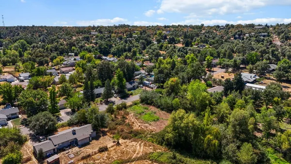 an aerial view of residential houses with outdoor space and trees