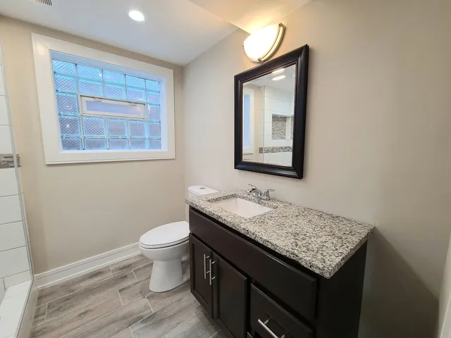 a bathroom with a granite countertop sink toilet and mirror