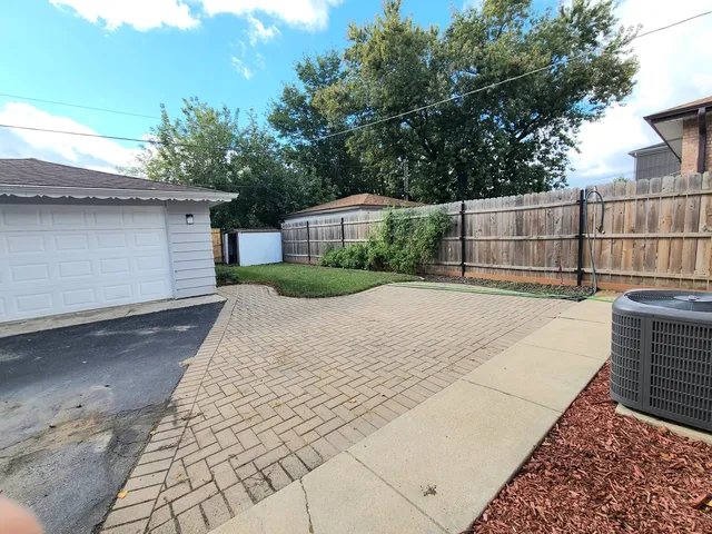a view of backyard with large tree and wooden fence