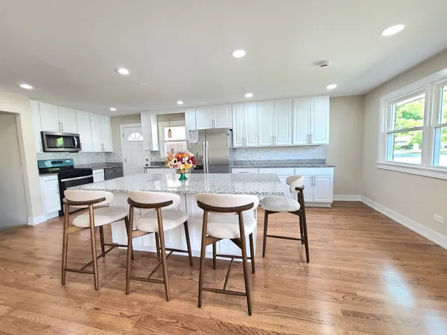 a kitchen with stainless steel appliances wooden floor dining table and chair