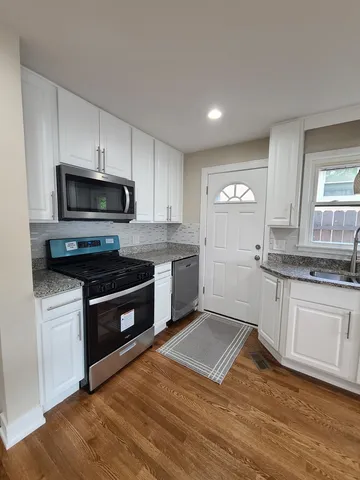 a kitchen with granite countertop a stove a sink and a microwave