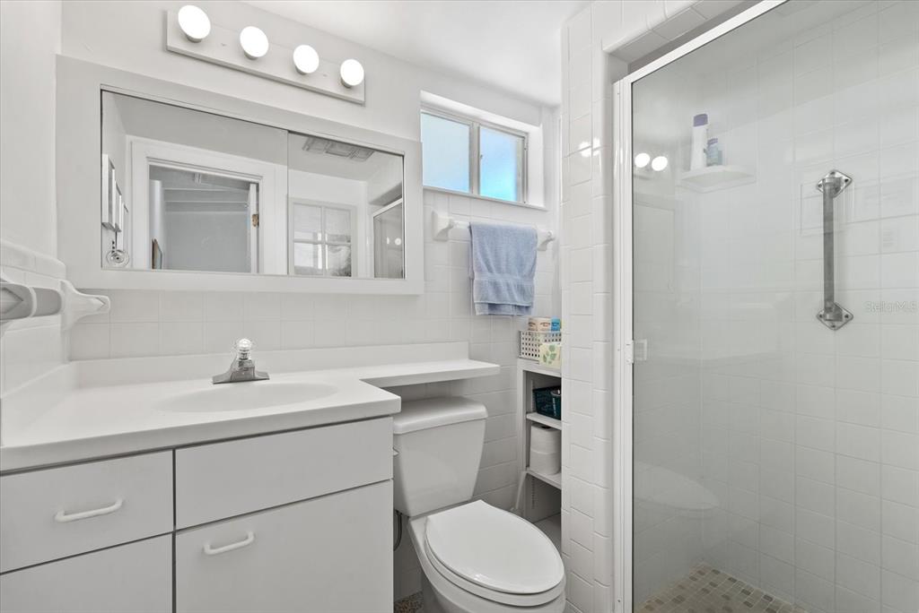 6006 Midnight Pass Road, Unit 11 Sarasota, FL 34242 - Photo 12 of 45 a bathroom with a toilet sink a mirror and vanity