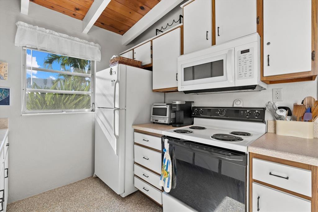6006 Midnight Pass Road, Unit 11 Sarasota, FL 34242 - Photo 9 of 45 a kitchen with stainless steel appliances granite countertop a refrigerator and a stove top oven