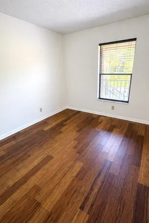 a view of an empty room with wooden floor and a window