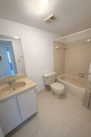 a bathroom with a granite countertop sink a toilet a mirror and bathtub