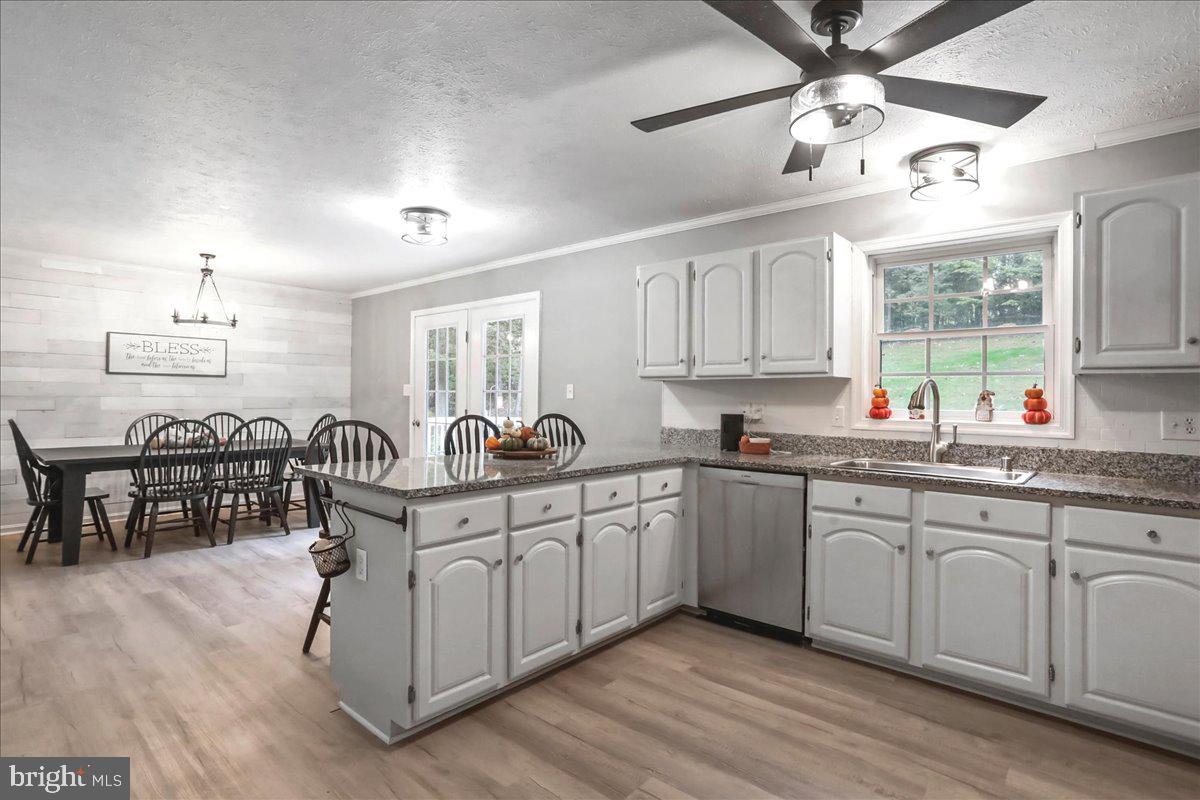 2726 Cave Ridge Road Mount Jackson, VA 22842 - Photo 7 of 39 a kitchen with granite countertop lots of white cabinets a sink dishwasher a dining table and chairs with wooden floor