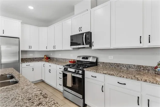 a kitchen with granite countertop white cabinets and stainless steel appliances