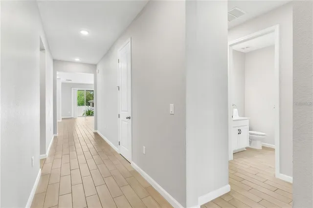 a view of a hallway with wooden floor and a bathroom