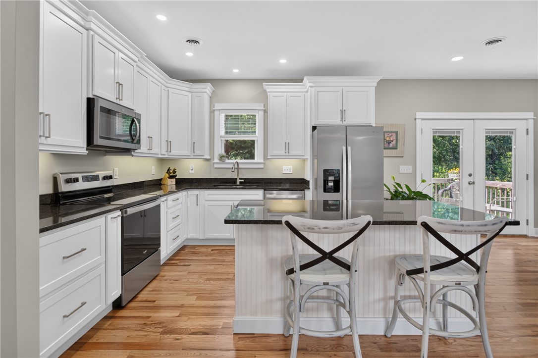 405 Pawnee Drive Walhalla, SC 29691 - Photo 2 of 36 A contemporary kitchen showcasing rich hardwood floors and sleek stainless steel appliances, complemented by elegant granite countertops.