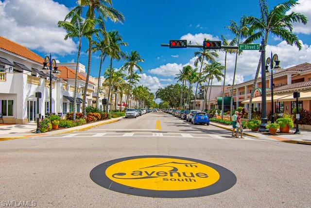 1251 7th Avenue North, Unit 307 Naples, FL 34102 - Photo 22 of 23 a view of a swimming pool with a lawn chairs under an umbrella