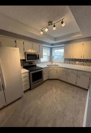 a kitchen with granite countertop a stove top oven and cabinets