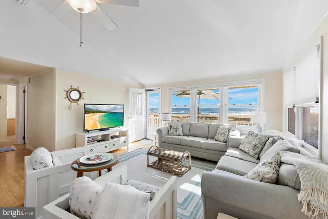 a living room with furniture a floor to ceiling window and a flat screen tv