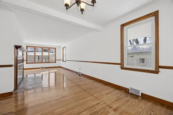 a view of an empty room with window and wooden floor
