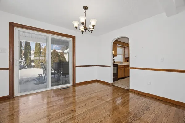 a view of a hallway with wooden floor and a chandelier