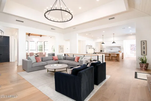 a living room with furniture kitchen view and a chandelier