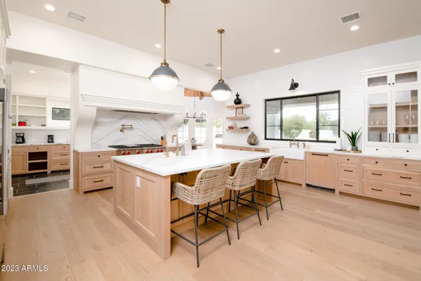 a large kitchen with kitchen island a stove a sink a center island and a wooden floor