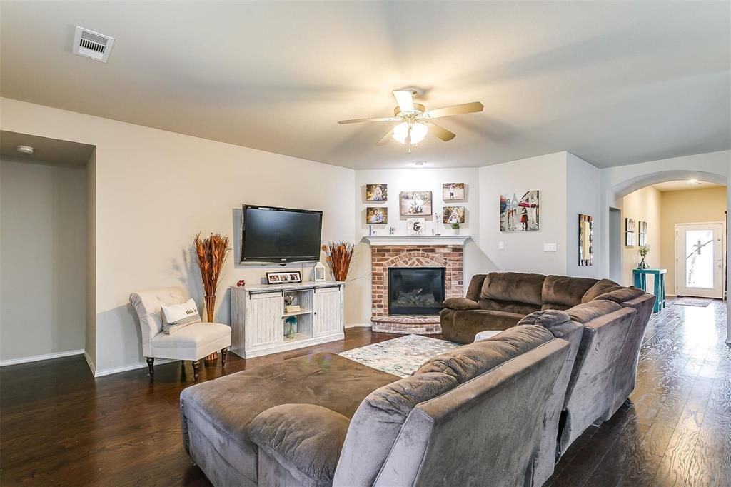 1629 Ridge Creek Lane Aubrey, TX 76227 - Photo 7 of 25 Living room with arched walkways, dark wood-type flooring, ceiling fan, and a brick fireplace