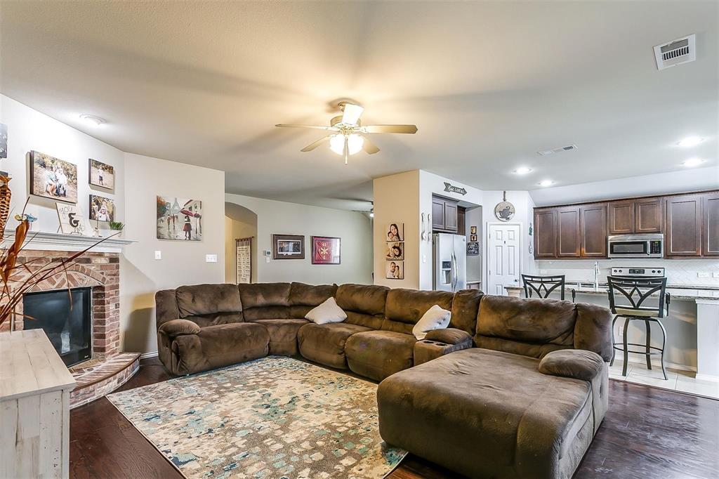 1629 Ridge Creek Lane Aubrey, TX 76227 - Photo 8 of 25 Living room with a brick fireplace, dark wood-style flooring, a ceiling fan, recessed lighting, and arched walkways
