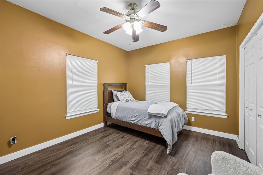 331 Radecke Road Krum, TX 76249 - Photo 29 of 40 Bright interior room featuring a wood-finish flooring, two windows with blinds, a ceiling fan with light fixture, and white bi-fold closet doors