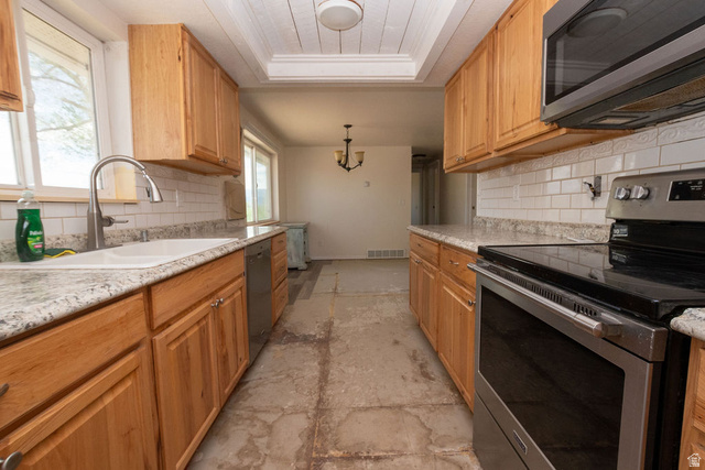 570 West Main Street Beaver, UT 84713 - Photo 13 of 43 Kitchen featuring light wood cabinetry, white subway tile backsplash, granite-finish countertops, stainless steel appliances, and a recessed ceiling with wood paneling