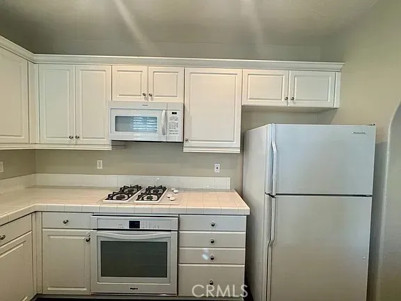 a kitchen with white cabinets and white appliances