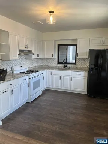 a kitchen with granite countertop a sink stainless steel appliances and cabinets