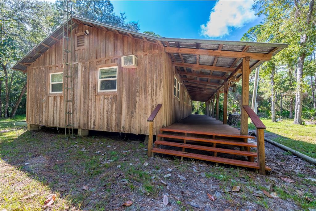 6550 Southwest 100 Court Cedar Key, FL 32625 - Photo 10 of 41 a backyard of a house with barbeque oven wooden fence and trees
