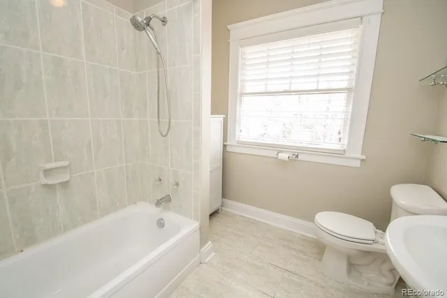 a bath room with a toilet a bath tub and a window