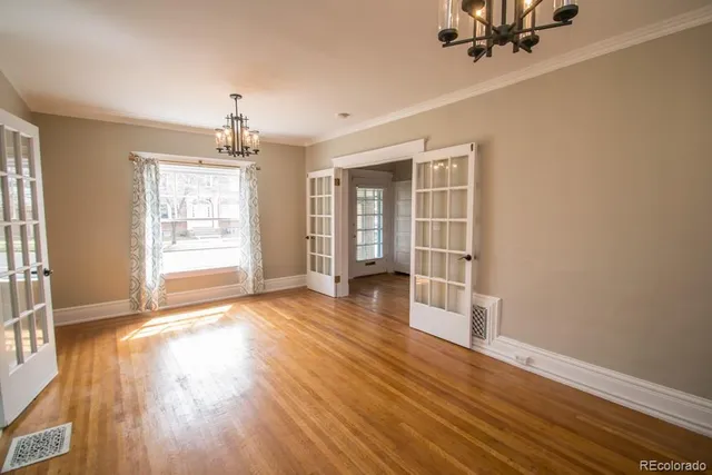 a view of an empty room with a window and wooden floor