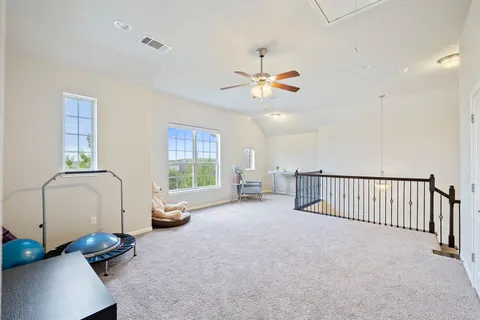 an empty room with windows and ceiling fan