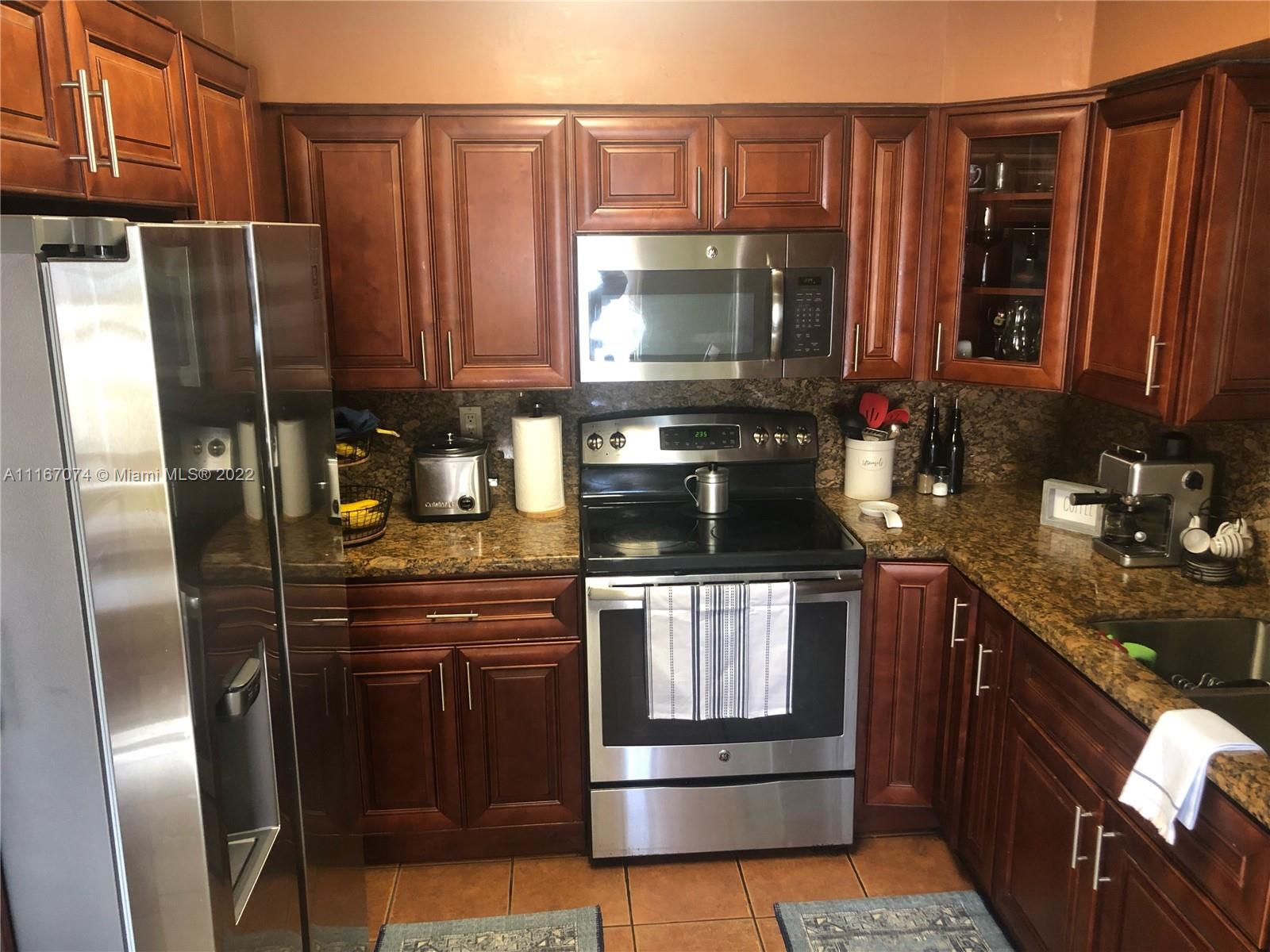 172 West 17th Street Hialeah, FL 33010 - Photo 9 of 27 a kitchen with stainless steel appliances granite countertop a refrigerator a stove and a sink with wooden cabinets