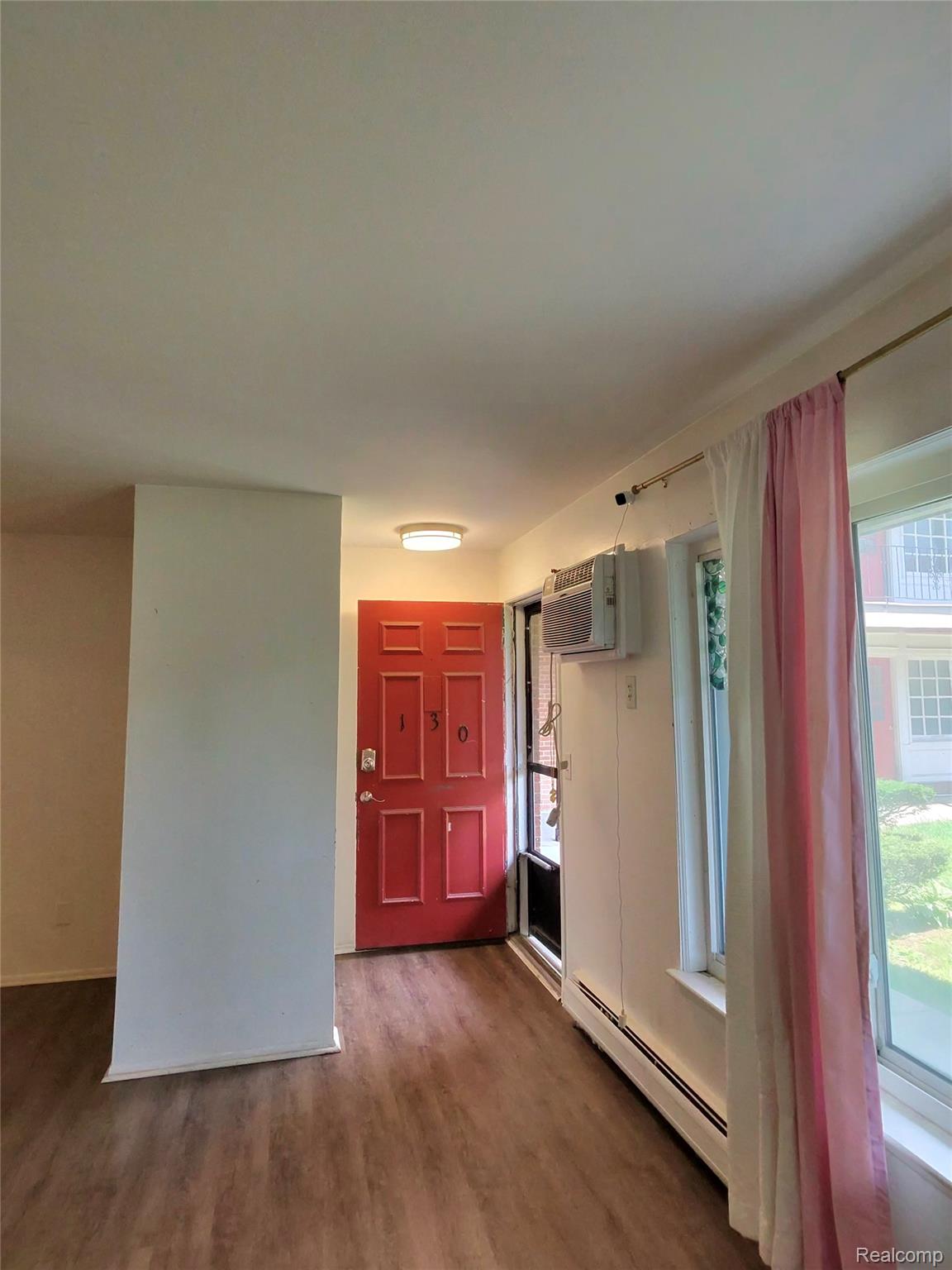 25301 Five Mile Road, Unit 130 Redford, MI 48239 - Photo 2 of 15 Entry area featuring a bright red paneled door with hardware, wood-finish flooring, and a flush-mount ceiling light