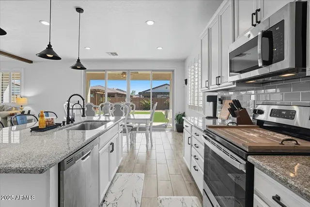 a kitchen with stainless steel appliances granite countertop a sink a stove and a wooden cabinets