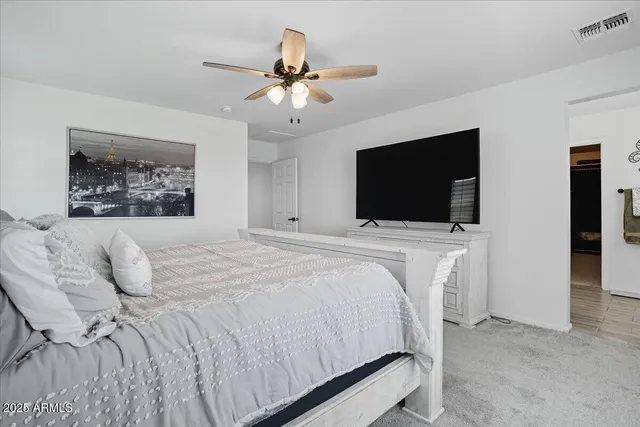 a bedroom with a bed a flat screen tv and a chandelier
